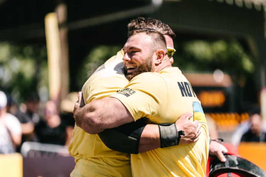 two men in yellow t shirts hug and smile