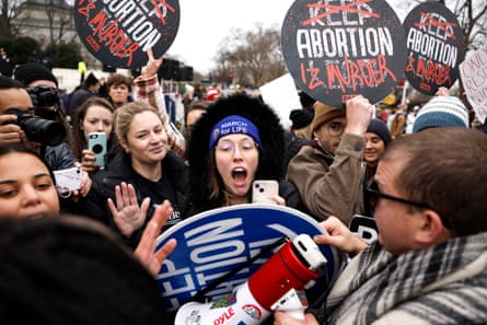 las personas sostienen carteles que dicen 'mantener el aborto legal' pero las palabras están tachadas para que digan 'aborto es asesinato'