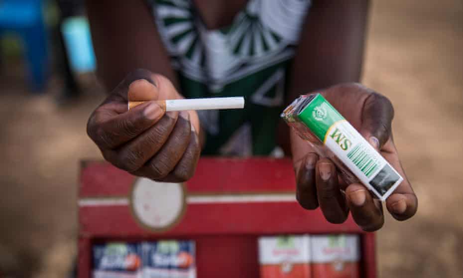 A woman selling tobacco holds out a single cigarette