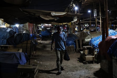 A man walks through a market at night in the Kalerwe area of Kampala, Uganda