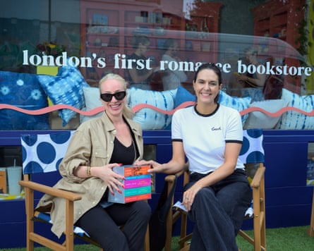 Haley Page and Rebecca Pollard sitting on chairs outside Saucy Books. Haley is holding the Sarah J Maas Acotar series
