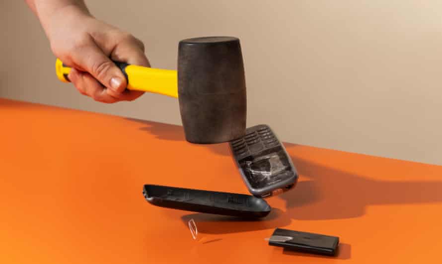 James Ball smashes a Nokia mobile phone with a large hammer against an orange background
