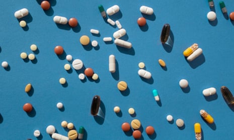 different kinds of coloured pills scattered on a blue background