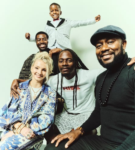 A group of four adults and one child smile at the camera.