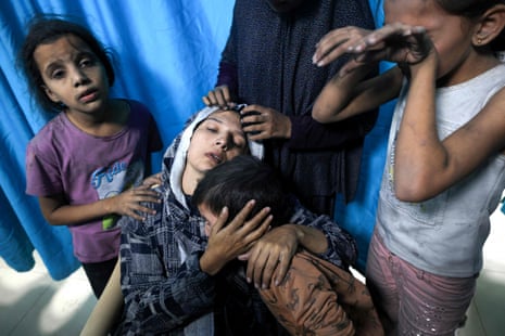 A wounded Palestinian woman is surrounded by her children at Nasser hospital