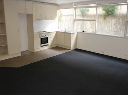 The kitchen and lounge room of a unit with windows that look out at a concrete wall