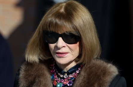 Anna Wintour in black sunglasses with fur-collared coat, and wearing a necklace with large different coloured stones