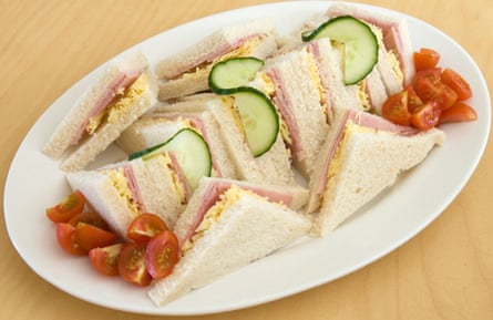 Cheese and ham salad sandwiches on a plate, with additional cucumber and tomato