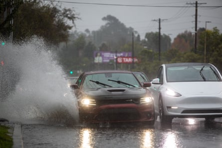 water from road splashes as cars drive in rain