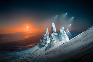 Drone shine lights on to snow and ice-covered rock formations at night
