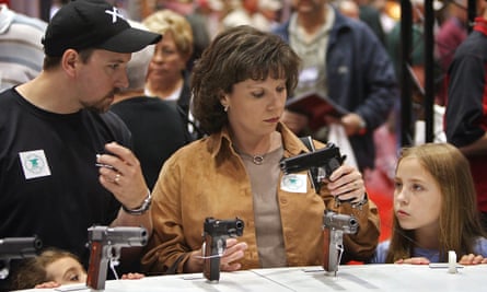 Parents and their daughters, nine- and five-years-old, look over a pistol at the National Rifle Association of America’s 2008 meeting.
