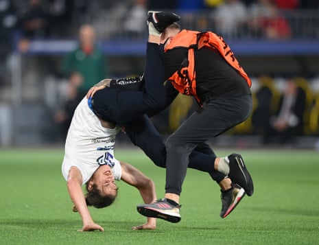 A pitch invader is tackled down by a steward.