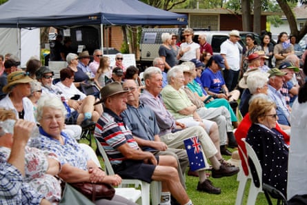 People sit in chairs on the grass at an Australia Day ceremony