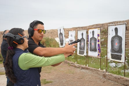 man and woman hold gun together near targets