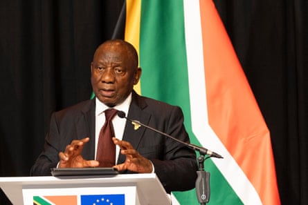 he stands at a podium in front of a South African flag.