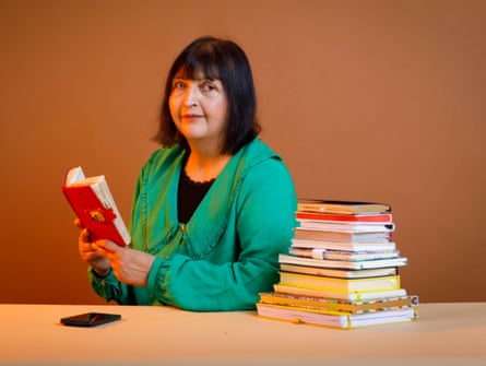 A woman holding a red diary with a stack of diaries beside her