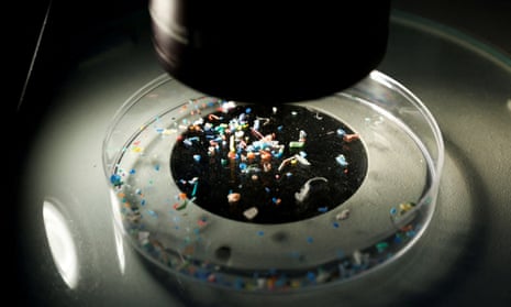 A microscope is focused on a petri dish full of colorful bits of microplastics.