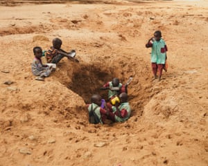 Children fill their water bottles from a hole dug into the dried Ewaso Nyiro riverbed, Samburu, Kenya.