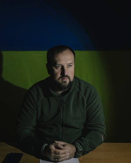 The mayor of Kupiansk, Andrii Besiedin, looking sombre while sitting in front of the Ukrainian flag
