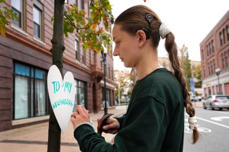 Miia Zellner, an art teacher from Turner, Maine, attaches a heart cut-out with a message of positivity to a tree in downtown Lewiston, Maine, Thursday, Oct. 26, 2023.