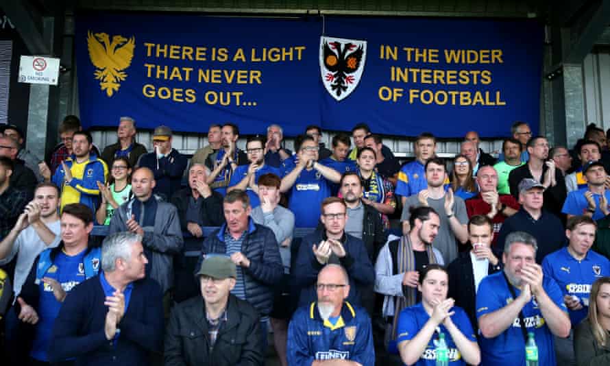 The battle for Wimbledon: realpolitik versus romance in football | AFC Wimbledon 4 AFC Wimbledon fans with a banner referring to the 2002 report at a Carabao Cup game against MK Dons in August 2019