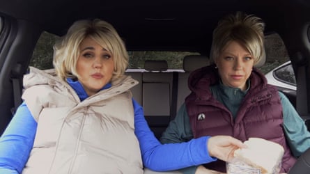 Ellie White and Natasia Demetriou sit in a car, one holding a sandwich