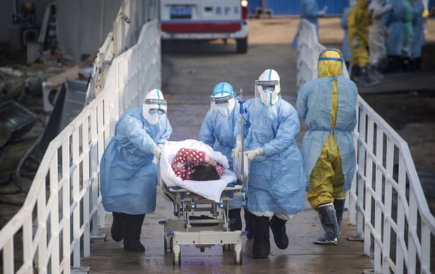 Medical workers in protective suits help transfer suspected coronavirus patients into the Huoshenshan temporary field hospital in Wuhan, in central China’s Hubei province