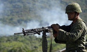 A Mexican soldier of the 88th infantry brigade patrols as smoke rises after a military helicopter was shot down in Jalisco on Saturday.