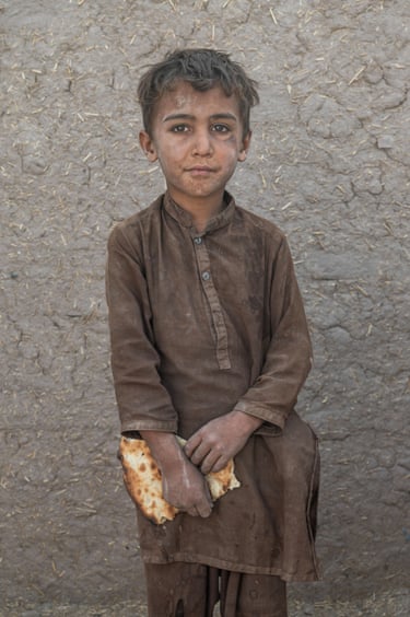 A young boy covered in dust hold a piece of flatbread