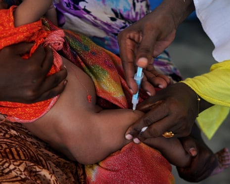 A baby is held while an injection goes into its leg