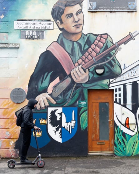 A man rides a scooter past an Irish republican mural in west Belfast, Northern Ireland in March 2023.