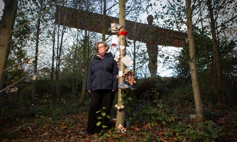 Prof Anne Whitehead stands next to a tree adorned with memorial items in the shadow of Antony Gormley's Angel of the North
