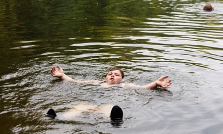 A boy called Dominic floating on his back in a lake while wild swimming