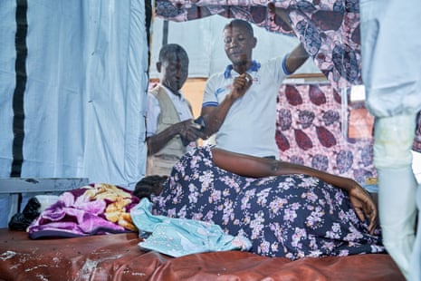 A pregnant woman lies on a bed while medical staff attend to her in an Ebola treatment centre