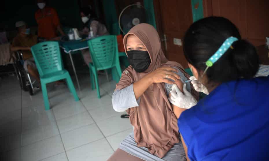 A healthworker administers a Covid jab to a woman during a vaccination program for refugees and asylum seekers in Jakarta, Indonesia.