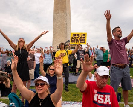 A person among a crowd of worshippers holds aloft a sign that reads ‘Jesus saves’