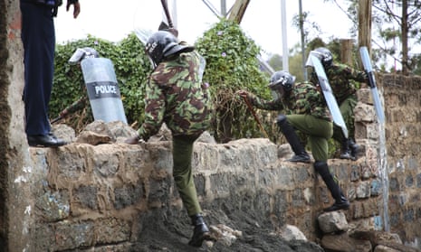 Riot police jump a wall during a running battle with opposition supporters in Kibera, Nairobi, on Thursday