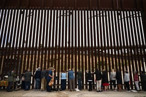 People lay their hands on the border wall and pray towards Mexico during pastor Seth Clark’s last service for the Border Church before his retirement in San Diego