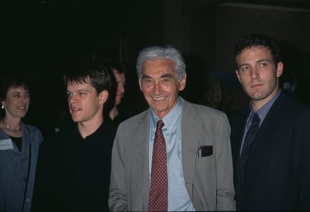 older man in suit smiling, flanked by two younger men