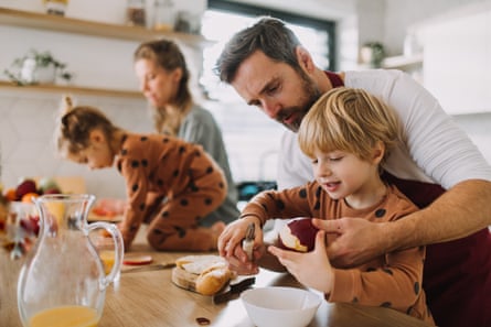 A young family with two little children preparing breakfast together in the kitchen.