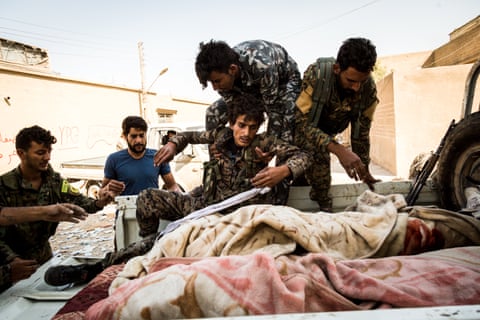 Syrian Democratic Forces fighters help a wounded comrade on to the back of truck in Raqqa.