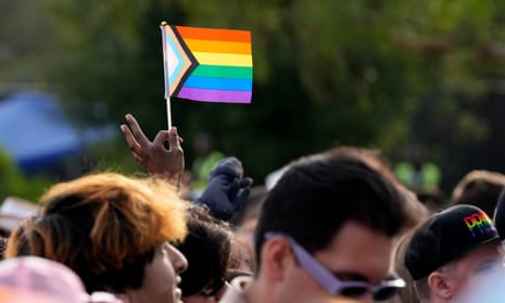 person holding a pride flag above people's heads