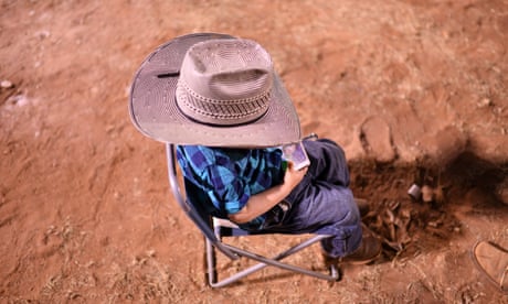 A young boy in a cowboy hat plays a game on a mobile phone at the Mount Isa Mines Rotary Rodeo, Friday, August 10, 2018. This is the 60th anniversary of the rodeo, the biggest of its kind in the Southern Hemisphere. (AAP Image/Dan Peled) NO ARCHIVING