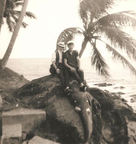 Barry Coaker and his friend sitting on a rock at the beach with palm trees in the background