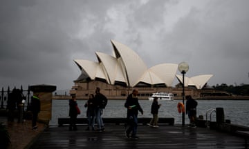 The Opera House is seen as people walk by in Sydney