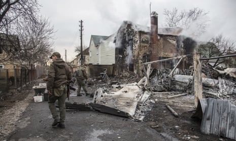 Ukrainian servicemen walk by fragments of a downed aircraft in Kyiv.
