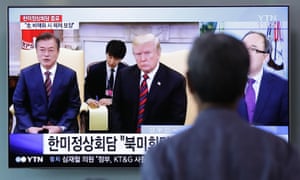 A man watches a TV screen showing Donald Trump and Moon Jae-in