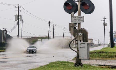 A car travels through a flooded street in Galveston, Texas. 