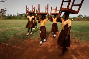 Schoolgirls in Ghana help prepare for the opening of the Maranatha Maternity Clinic by carrying chairs to the ceremony.