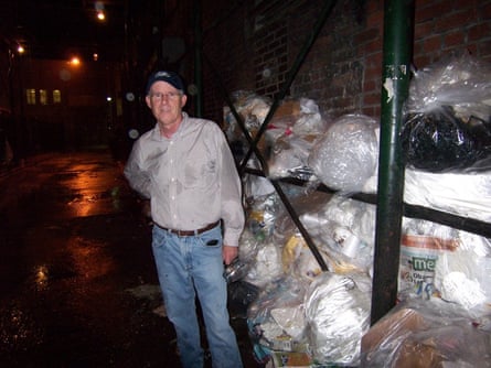 Corrigan stood next to container full of rubbish bags at night